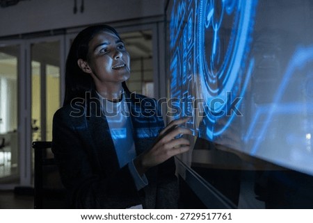 A professional man interacts with a high-tech circular data interface on a large digital screen, featuring graphs and data elements in a glowing blue theme.