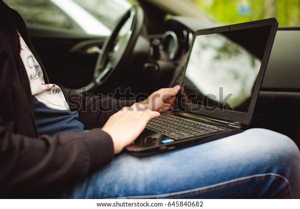 Professional man with a laptop in car tunes tuning\
control system, updating software, gaining access through to\
computer, sitting in\
cabin