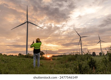 Professional Man Maintenance engineers working in wind turbine farm at sunset.  Engineer Man standing among Wind Energy Turbine. - Powered by Shutterstock