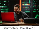 Professional man smiling while working on a laptop in a data center, managing server racks. Focusing on cybersecurity