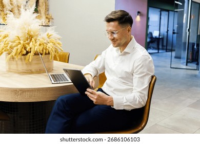 Professional man using tablet while sitting at modern workspace