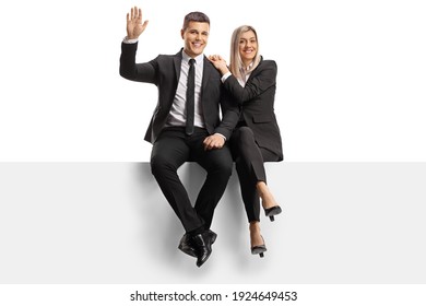 Professional Man And Woman In Business Clothes Sitting On A Blank Panel And Waving Isolated On White Background