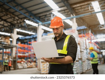 Professional manager man employee using laptop check stock working at warehouse. Worker wearing high visibility clothing and a hard hat, helmet and checking and count up goods or boxes for delivery. - Powered by Shutterstock