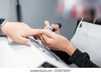 Professional manicurist woman holds woman's hand and does manicure, polishes nail - Powered by Shutterstock