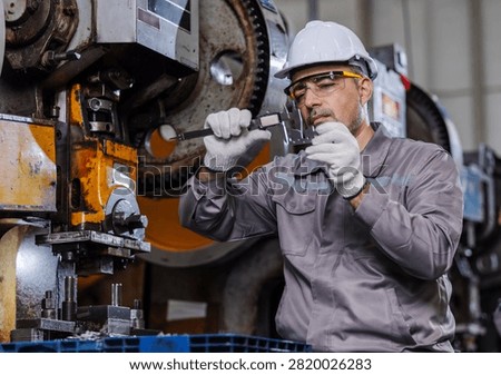 Professional manufacturing engineer inspecting a precision metal component with a digital caliper in a modern industrial factory.