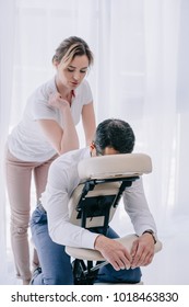professional masseuse doing seated back massage for businessman