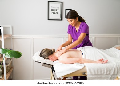 Professional Masseuse Giving A Back And Shoulder Massage To A Older Caucasian Woman At The Beauty Spa