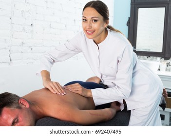 Professional Masseuse Performing Back Massage To Male Client In Spa Center