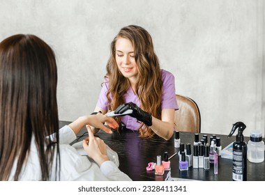 Professional master manicurist at beauty salon. Manicure service, hands treatments, procedures for nails, fingers. Multi-colored nail polish, samples palette, tattoos, cuticle oil, gel uv lamp,gloves. - Powered by Shutterstock