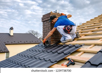 a professional master (roofer) with electric screwdriver covers repairs the roof - Shutterstock ID 1239738700