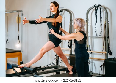 Professional Mature Female Fitness Coach Teaching Girl On Pilates Reformer Bed. Rehabilitation, Healthy Lifestyle, Small Business Concept.