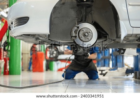 Professional mechanic changing a new tire. Disc brake on car in process of new tire replacement. The rim is removed showing the rotor and brake mechanism of the car wheel. Repair car for safety