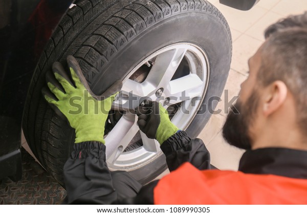Professional\
mechanic changing tire in car service\
center