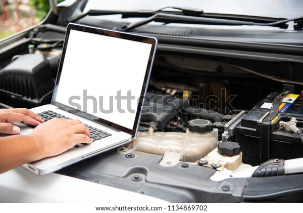 Professional mechanic checking\
car engine search for data with laptop and connect data system on\
car