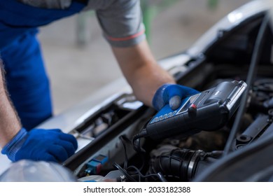 Professional Mechanic Doing A Car Inspection, He Is Using A Battery Tester