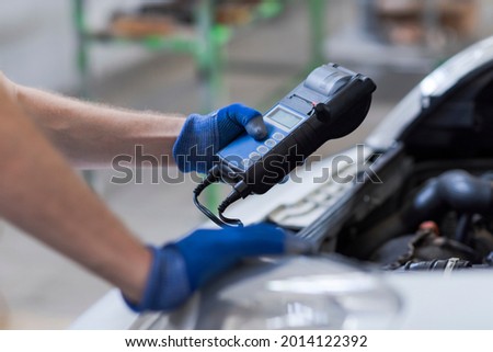 Professional mechanic doing a car inspection, he is using a battery tester