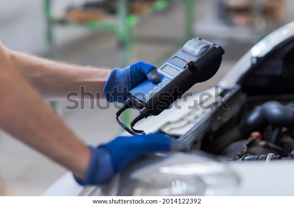 Professional mechanic doing a car inspection, he\
is using a battery\
tester