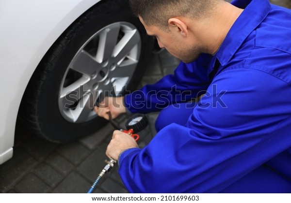Professional mechanic inflating tire at car\
service, closeup