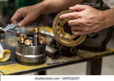 Professional Mechanic Man Holding Valve Plate Of The Hydraulic Piston Pump To Inspection And Repair Maintenance Heavy Machinery 