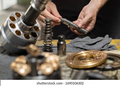 Professional Mechanic Man Holding Valve Rod Of The Hydraulic Piston Pump To Inspection And Repair Maintenance Heavy Machinery 