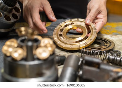 Professional mechanic man holding Valve plate of the hydraulic piston pump to inspection and repair maintenance heavy machinery 