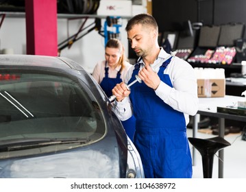 Professional Mechanic Performing Dent Repair On Car Body Before Painting In Auto Workshop