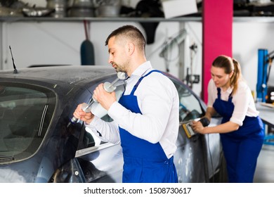 Professional Mechanic Performing Dent Repair On Car Body Before Painting In Auto Workshop