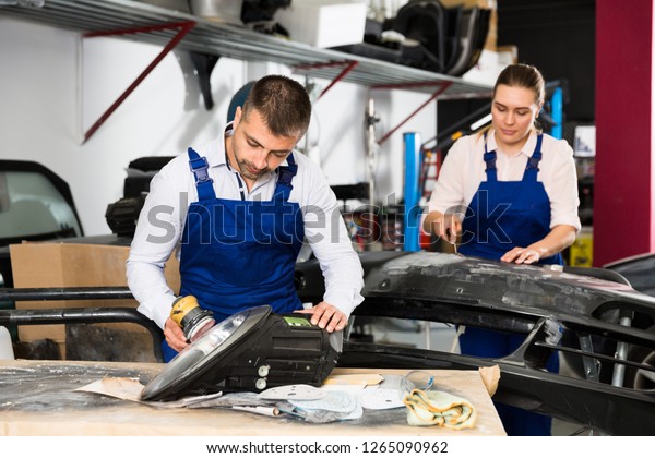 Professional mechanic performing polishing of\
headlight in automobile\
workshop