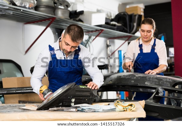 Professional mechanic performing polishing of\
headlight in automobile\
workshop