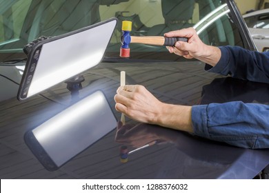 Professional mechanic removes dents on the car body