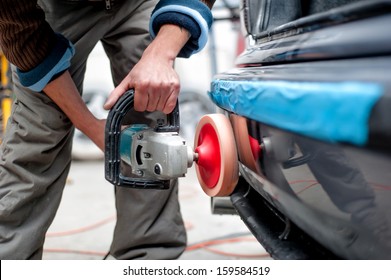 professional mechanic using a power buffer machine for cleaning the body of a car from scratches. Detail of car care concept