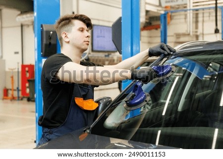 Professional mechanic using suction pads on car windscreen