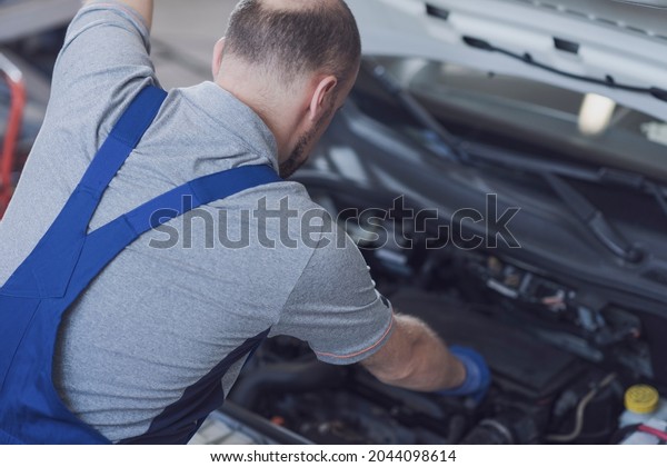 Professional mechanic at work, he is checking the\
car engine