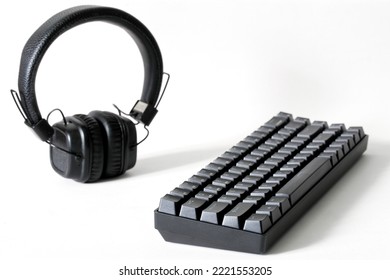 Professional Mechanical Computer Keyboard And Wireless Headphones On A White Background. Audio Recording Studio, Audio Streaming And Digital Audio Broadcasting. Copy Space. Selective Focus. Close-up