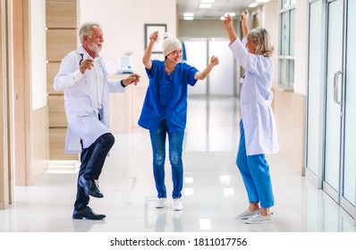 Professionelles Medizinerteam mit Stethoskop in gleichmäßiger Diskussion und Tanz mit glücklicher Patientin mit Krebserkrankung Kopf mit Kopftuch Chemotherapie Krebs im Krankenhaus.Gesundheitswesen 