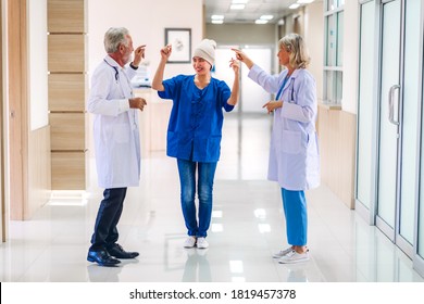 Professionelles Medizinerteam mit Stethoskop in gleichmäßiger Diskussion und Tanz mit glücklicher Patientin mit Krebserkrankung Kopf mit Kopftuch Chemotherapie Krebs im Krankenhaus.Gesundheitswesen 