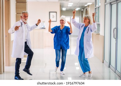 Professionelles Medizinerteam mit Stethoskop in gleichmäßiger Diskussion und Tanz mit glücklicher Patientin mit Krebserkrankung Kopf mit Kopftuch Chemotherapie Krebs im Krankenhaus.Gesundheitswesen