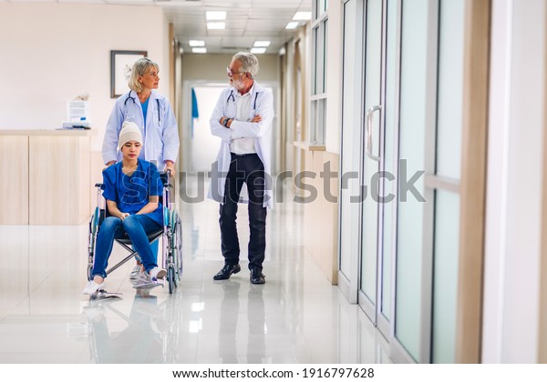 Professional\
medical doctor team with stethoscope in uniform discussing with\
patient woman with cancer cover head with headscarf of chemotherapy\
cancer in hospital.health care\
concept