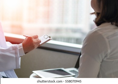 Professional Medical Doctor In White Uniform Gown Coat Interview Counselling Female Patient: Physician Writing On Patient Chart While Consultation: Hospital/ Clinic Healthcare Professionalism Concept