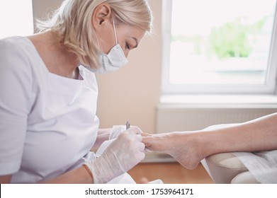 Professional medical pedicure procedure close up using nail clippers instrument. Patient visiting chiropodist podiatrist. Foot treatment in SPA salon. Podiatry clinic. Pedicurist hands in white gloves