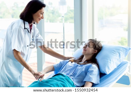 Professional medical service concept. Caucasian doctor smiling take care of a young patient girl in hospital. Friendly nurse or therapeutic treat client to be happy in nursing home.