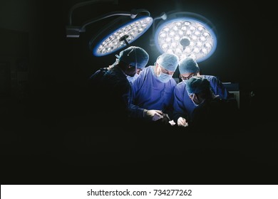 Professional medical team performing surgery in hospital. Group of surgeons at work in operation theater.