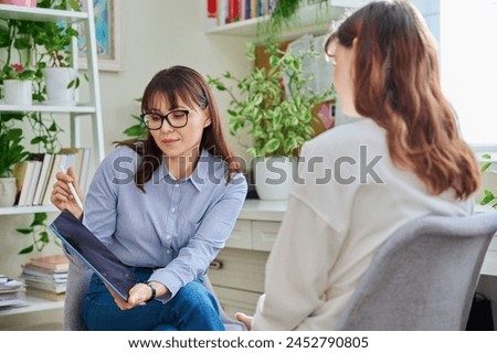 Professional mental therapist working with young woman, sitting together in office
