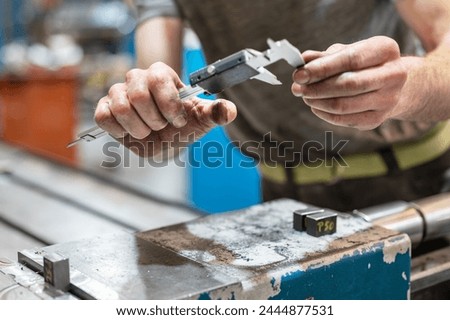 Professional metalworker using a caliber at the manufacture workshop. High quality photography