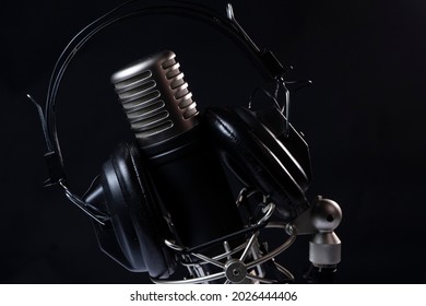 Professional microphone with black headphones over black background