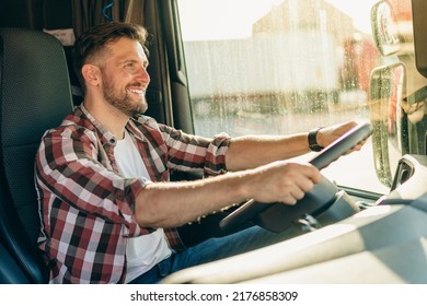 Professional middle aged truck driver in casual clothes driving truck vehicle going for a long transportation route.