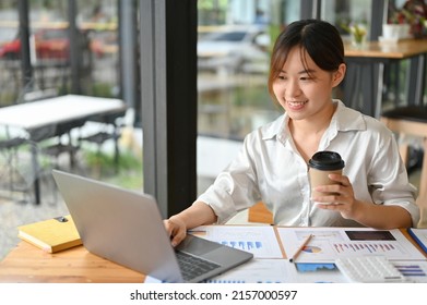 Professional Millennial Asian Businesswoman Or Financial Analysts Working On Financial Data Work And Sipping Afternoon Coffee, Sitting In The Coffee Sop. Remote Working