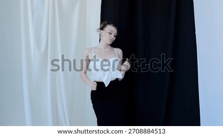 Professional model posing in a chic white top and black skirt against a striking black and white backdrop, embodying contemporary elegance and fashion forward style