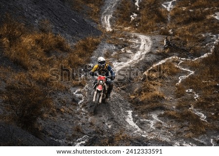 Professional motorcyclist in full moto equipment riding crops enduro bike in mountains, enduro driver rides through mud and puddles in the rain, motorcycle race Stock photo © 