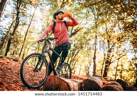Professional mountain bike cyclist riding trail in forest, details of sports. Drinking cold fresh water.